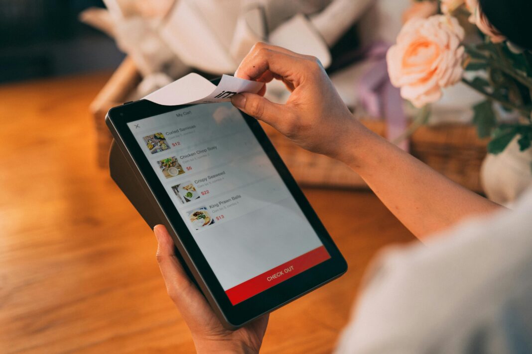 Person placing order on tablet using Swiggy Desk Eats for lunch at work with a receipt printing out.
